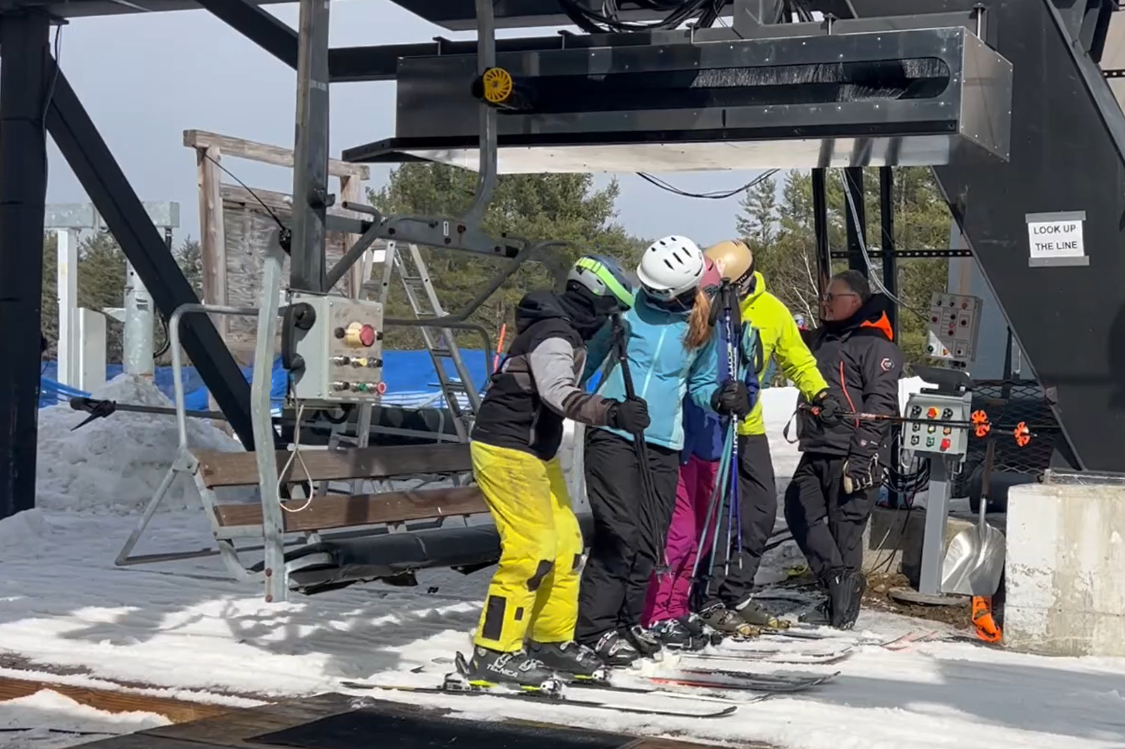 Skiers and lift attendants in an Auto Bump chairlift loading area
